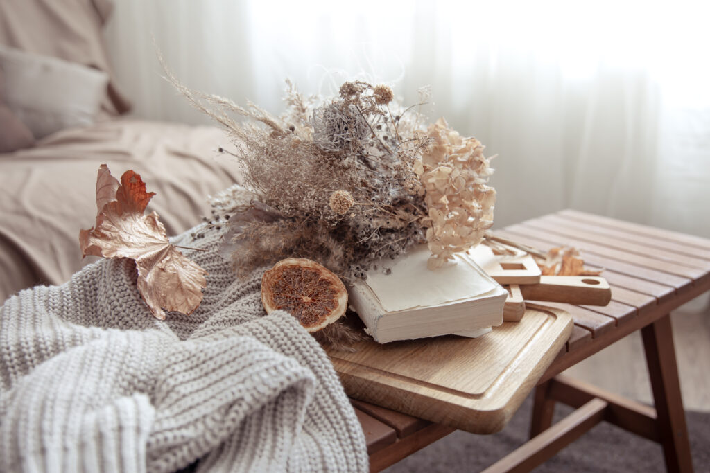 Bouquet de fleurs aux couleurs automnales, un pull gris et un livre blanc